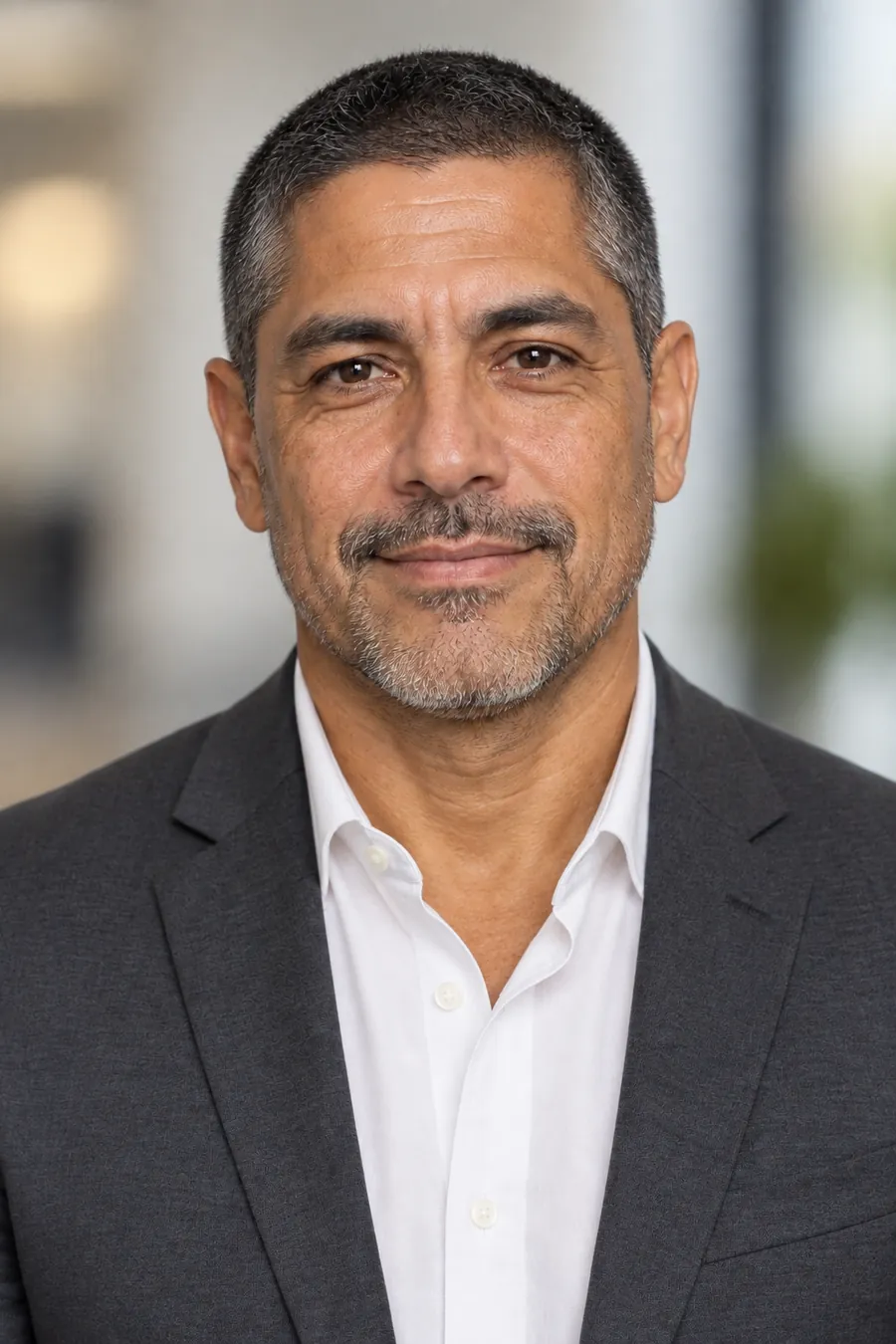 Richard Enes, AI-generated model, corporate headshot in a grey suit